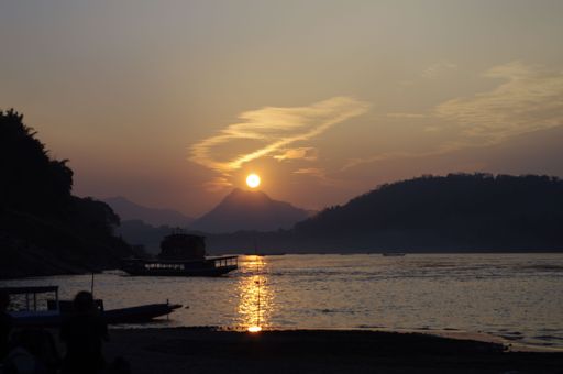 A scenic view of a tranquil lake situated in the foreground of a majestic mountain range at sunset.