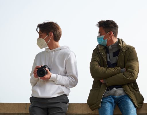 A closeup of two young Caucasian and Hispanic guys wearing sanitary masks outdoors