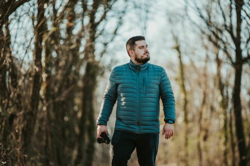 A handsome Caucasian male with camera in hand walking in a forest