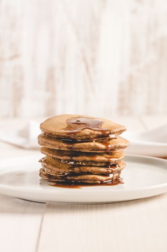 A beautiful shot of pancakes covered in maple syrup