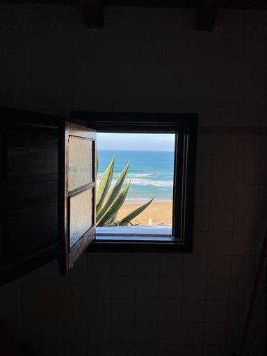 An open window with a tropical tranquil beach scene in the background