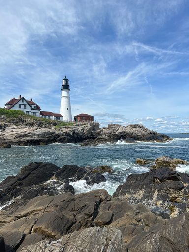 The Lighthouse on the ocean in Portland Maine with rocks on the shore