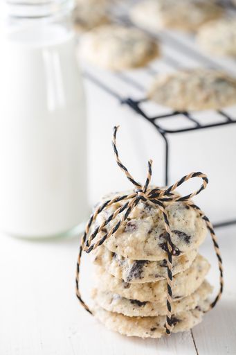 A selective focus shot of tied chocolate chip cookies next to a cup of milk