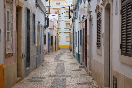 A narrow alley with a row of windows and shutters in Portugal