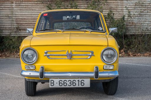 Front view of a small classic Spanish economy car, the Seat 850 in yellow color