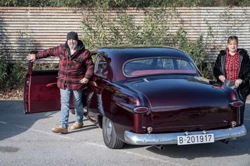 Rear view of a beautiful classic American car, the Ford '49 bullet nose in purple, the owner is getting out of the car