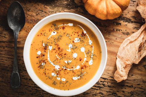 A top view shot of pumpkin soup on the wooden surface