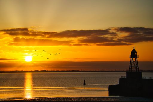 A tranquil scene of a lighthouse set against a beautiful golden sky