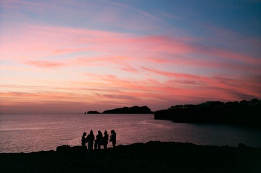 A group of young people come together at sunset to have fun on the beach