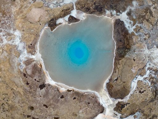 An aerial view of a stunning small blue lake situated in a rocky and mountainous terrain