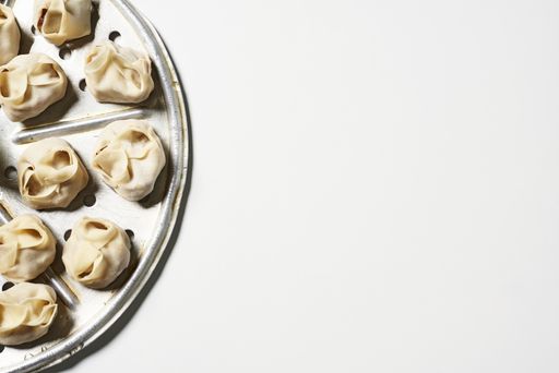 A top view of delicious homemade manti dumplings on a white surface with copy space