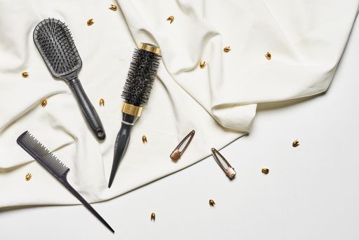 A top view of a plastic hair comb and brushes on the white fabric