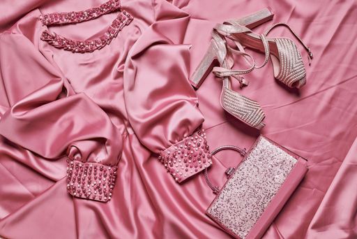A top view of an elegant and fashionable  silk dress with pearls, high heels, and a purse