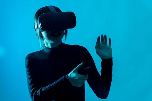 A portrait of a young brunette woman wearing VR glasses against a blue background