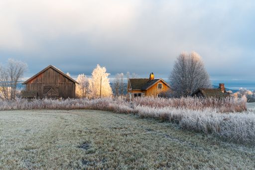 A scenic view of traditional wooden homes perched along the coast of majestic Lake Mjosa in Norway