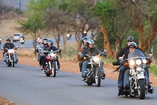 old motorcycles riding together with passengers on the tarmac