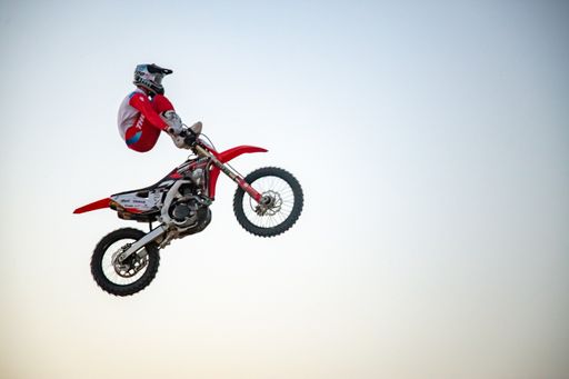 motocross freestyle riders and motorbikes jumping in desert with dunes and flames
