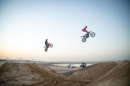 Freestyle motorcross riders and motorbikes in the desert jumping of dunes