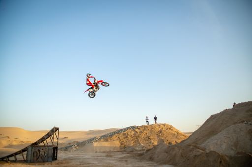 Freestyle motorcross riders and motorbikes in the desert jumping of dunes