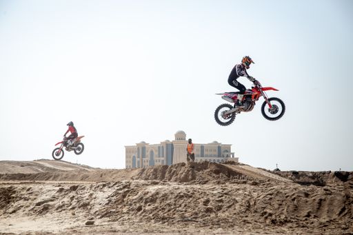Motorcross riders on sand racing with motorbikes and protective gear