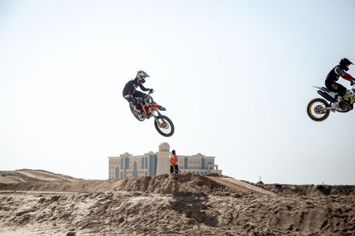 Motorcross riders on sand racing with motorbikes and protective gear