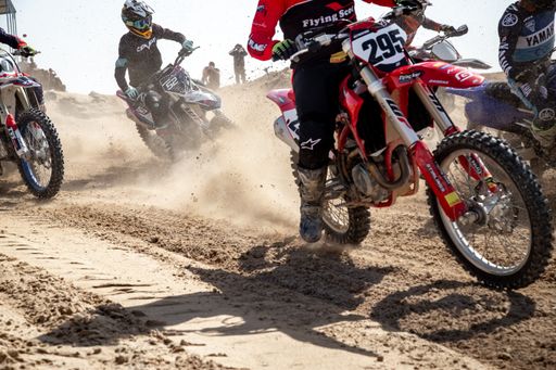 Motorcross riders on sand racing with motorbikes and protective gear
