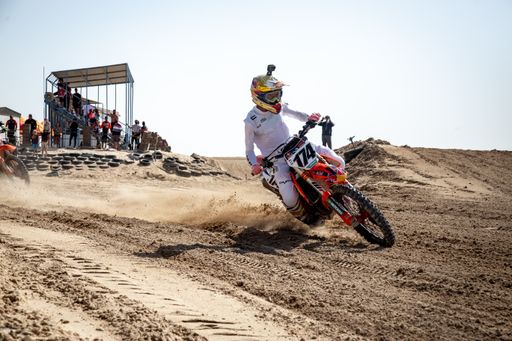 Motorcross riders on sand racing with motorbikes and protective gear
