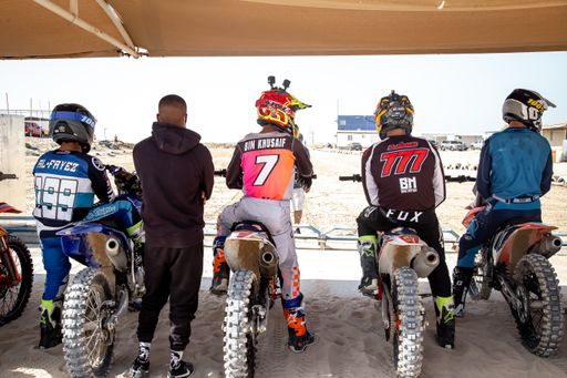 Motorcross riders on sand racing with motorbikes and protective gear