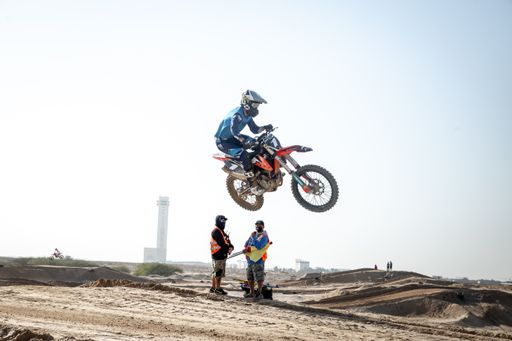 Motorcross riders on sand racing with motorbikes and protective gear
