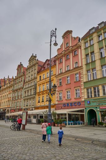 A vertical of people walking on a cobblestone-paved neighborhood in Wroclaw, Poland