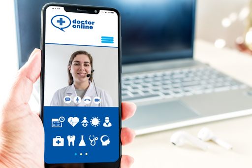 A selective focus of a hand holding a smartphone showing a healthcare app at a desk