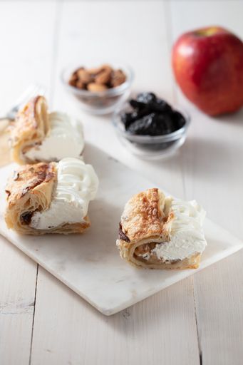 A top view shot of a dessert with cream, apple, almond, and dried fruits