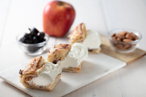 A top view shot of a dessert with cream, apple, almond, and dried fruits