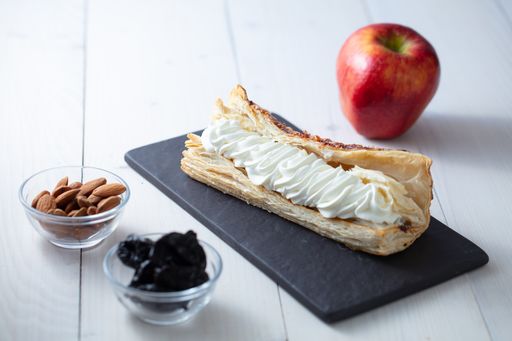 A beautiful shot of the creamy dessert on the plate, with an apple, almond and dried fruits next to it