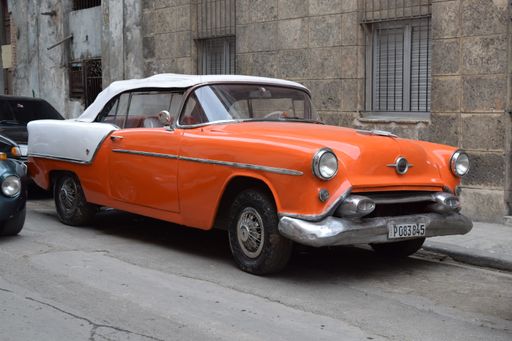 A closeup shot of a vintage orange Cadillac car parked on the street in Havana, Cuba