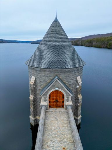 An ancient castle situated by a tranquil lake, featuring a wooden dock, and traditional windows