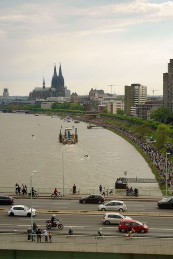 A vertical shot of a bustling street and the river Rhine on an overcast day