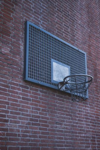A wide shot of an angle of a basketball ring on a brick wall of a building
