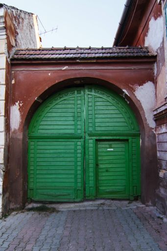 A vertical shot of an old building with green wooden doors under the sunlight