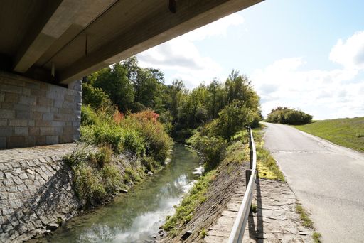 A beautiful view of a small river under a bridge near the road