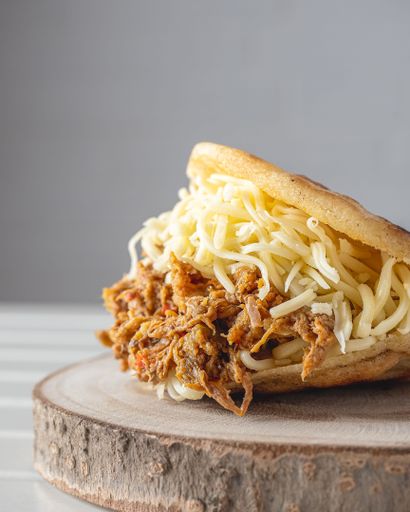 A vertical closeup of Venezuelan dish of carne mechada in arepa