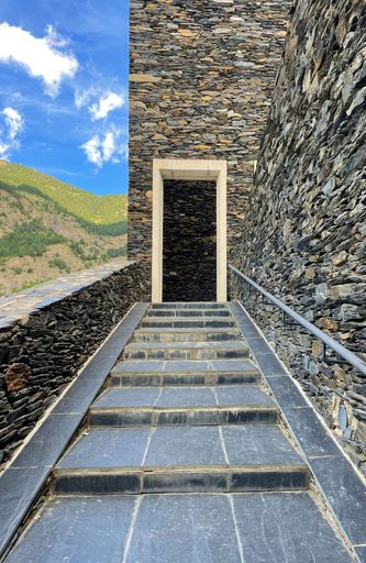 A winding stone stairway leading up to an ancient door in a rugged stone-walled structure