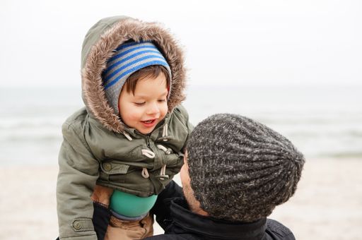 Man holding two years old boy at a beach on a cloudy day
