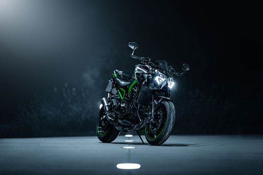 A green motorcycle parked under a spotlight in a dark setting