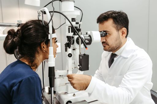 An ophthalmologist is performing a medical examination on a female patient in a laboratory setting.