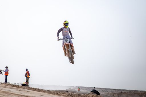 motorcross riding motorbike on sandy track during the day jumping