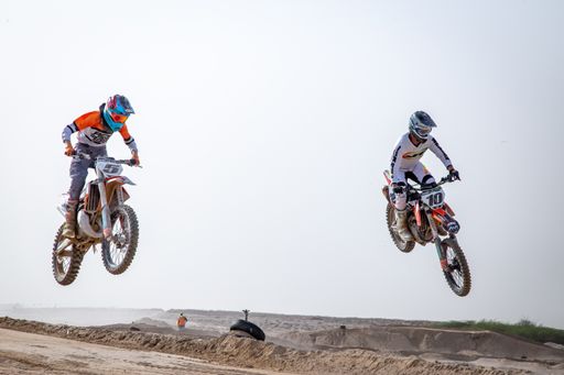motorcross riding motorbike on sandy track during the day jumping