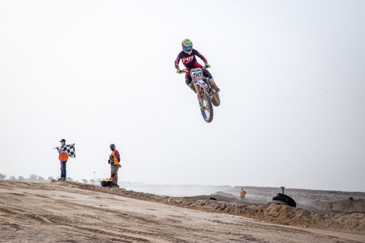 motorcross riding motorbike on sandy track during the day jumping