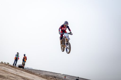 motorcross riding motorbike on sandy track during the day jumping