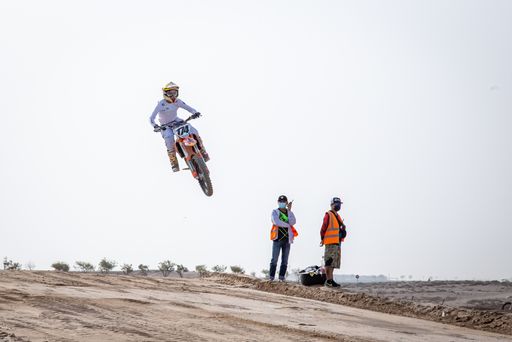 motorcross riding motorbike on sandy track during the day jumping